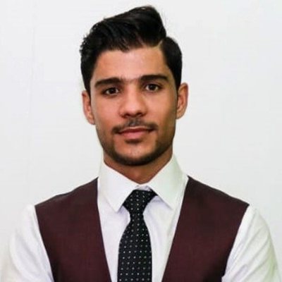 Syed Hassam Mehdi, smiling, in a white shirt, dark waistcoat and spotted tie